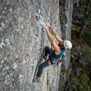 A rock climber clinging to a cliff face with arms and legs e