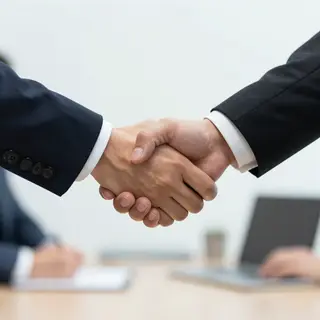 Two people shaking hands in a professional setting, all fing