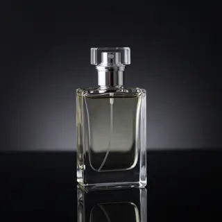 A clear glass perfume bottle on a reflective black surface w