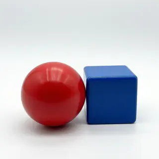 A red ball and a blue cube sitting side by side on a white s