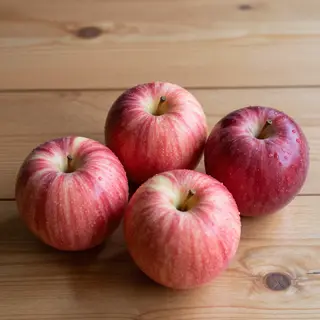 Exactly 3 red apples arranged on a wooden table