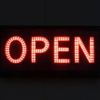 The word 'OPEN' displayed on a red LED sign with glowing pix