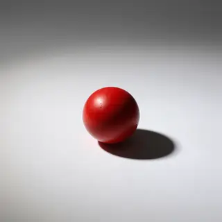 A red sphere on a white surface with a single shadow cast to