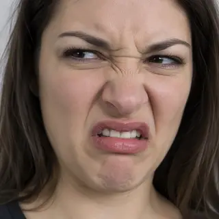 A close-up of a person's face showing clear disgust, nose wr