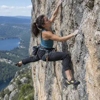 A rock climber clinging to a cliff face with arms and legs e