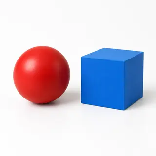 A red ball and a blue cube sitting side by side on a white s