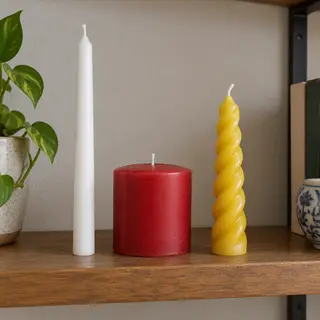 A tall thin white candle, a short fat red candle, and a medi