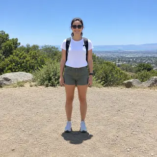 A person standing outdoors at midday with a short shadow dir