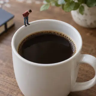 A tiny person standing on the rim of a coffee cup, looking d