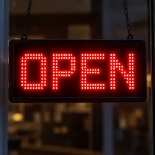 The word 'OPEN' displayed on a red LED sign with glowing pix
