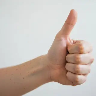 A hand giving a thumbs-up with four fingers curled and thumb