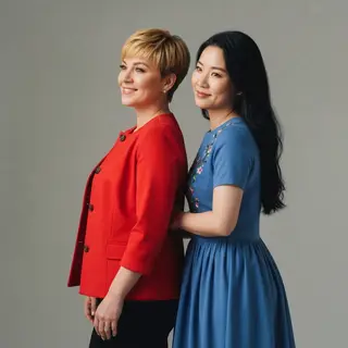 Two women standing side by side: one with short blonde hair 