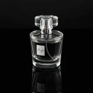 A clear glass perfume bottle on a reflective black surface w
