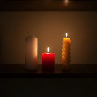 A tall thin white candle, a short fat red candle, and a medi