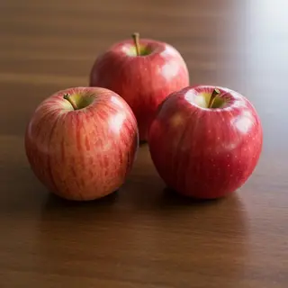 Exactly 3 red apples arranged on a wooden table