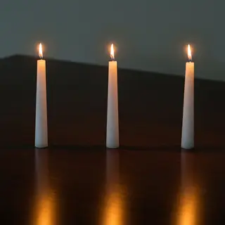 Exactly 4 white candles standing on a dark surface
