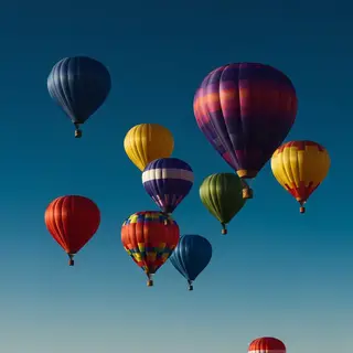 Exactly 11 colorful balloons floating against a clear blue s