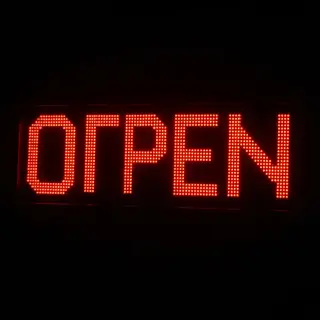 The word 'OPEN' displayed on a red LED sign with glowing pix