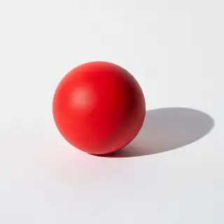 A red sphere on a white surface with a single shadow cast to