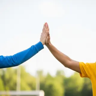Two people doing a high-five, palms meeting with all fingers