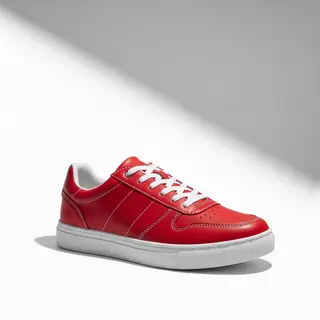 A single red sneaker on a clean white background with soft s