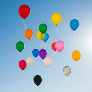 Exactly 11 colorful balloons floating against a clear blue s