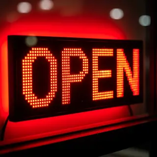 The word 'OPEN' displayed on a red LED sign with glowing pix