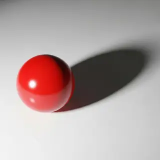 A red sphere on a white surface with a single shadow cast to