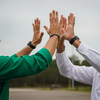 Two people doing a high-five, palms meeting with all fingers