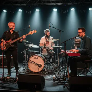 Three musicians on stage: a tall woman with short pink hair 