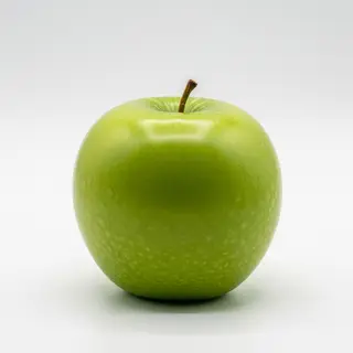 A ripe green apple on a seamless white background with soft 