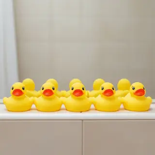Exactly 5 yellow rubber ducks sitting in a row on a bathroom