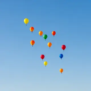 Exactly 11 colorful balloons floating against a clear blue s