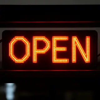 The word 'OPEN' displayed on a red LED sign with glowing pix