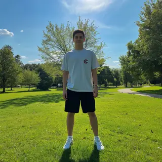 A person standing in a neutral pose in a park, full body vis
