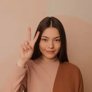 A person making a peace sign with their right hand, clearly 
