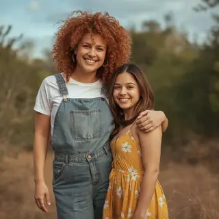 Two friends posing: one tall with curly red hair in denim ov