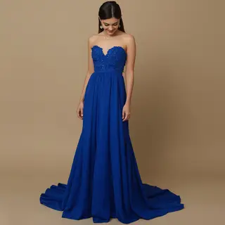 A woman wearing a royal blue evening dress against a neutral