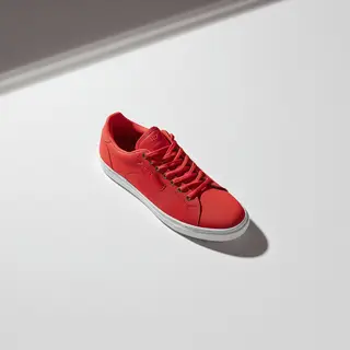 A single red sneaker on a clean white background with soft s