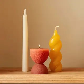 A tall thin white candle, a short fat red candle, and a medi