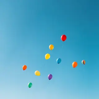 Exactly 11 colorful balloons floating against a clear blue s