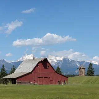 A landscape with a red barn in the foreground at large scale