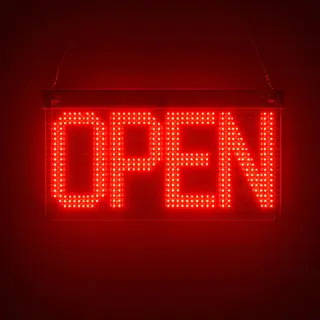 The word 'OPEN' displayed on a red LED sign with glowing pix