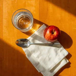 A still life on a wooden table featuring a clear glass of wa