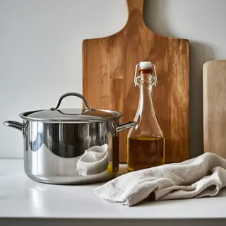 A kitchen counter with a stainless steel pot, a wooden cutti