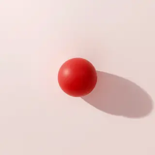 A red sphere on a white surface with a single shadow cast to