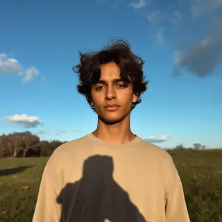 A person standing outdoors at midday with a short shadow dir