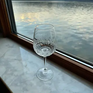 A crystal wine glass on a polished marble counter next to a 