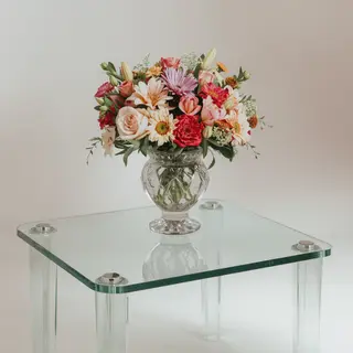 A vase of flowers on a glass table with a clear reflection v