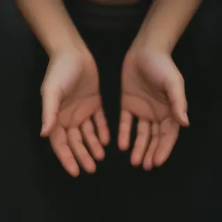 A person standing with both hands visible at their sides, fi